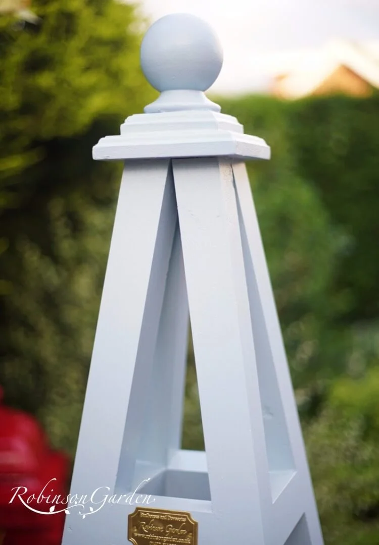 Bespoke wooden garden obelisk design hand painted in Lincolnshire, England, UK using Farrow & Ball exterior eggshell paint. Uniquely crafted using sustainable FSC certified timber / wood. Available in a range of sizes including 5ft (5 foot), 6ft (6 foot) and 7ft (7 foot) as well as trellised design, 8ft design available on request. We sell small garden obelisk, large garden obelisk and tall garden obelisk, The wooden obelisk design is different to Argos, B&M, ALDI, homebase, dobbies, gardman, home bargains, pets at home, B&Q, b & q, amazon, M&S, Robert dyas, rspb, ikea, john lewis, rhs, gumtree, asda, argos, wilkinsons, kingfisher, the garden obelisk company, QVC or any other garden centre. We are an online only store and we are not on the high street. We also have outlet shops across etsy and ebay UK. Not made from metal or copper. Our design plan, dimensions and height are suitable for climbing plants including Roses, sweet peas and is freestanding and a perfect gift for garden lovers. Wooden garden obelisk assembly free and no set up required. Visit out gallery to see all the wooden obelisk images. Wooden obelisk / garden obelisk delivered ready assembled. Perfect bird table for your garden, choice of ball, acorn and unique finial. Designs include Windsor wooden obelisk and Buckingham wooden obelisk. A smart English garden eiffel obelisk. Can be purchased as a set of 3 for your garden.