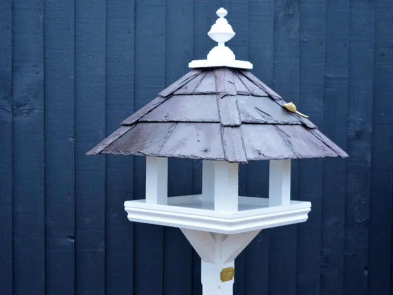 Bespoke bird table design with a slate roof hand painted in Lincolnshire, England, UK using Farrow & Ball exterior eggshell paint. Uniquely crafted using sustainable FSC certified timber / wood. This bird table and feeder is anti squirrel that doesn’t require anchoring pegs or to be attached to a fence. The bird table design is different to Argos, B&M, ALDI, homebase, dobbies, gardman, home bargains, pets at home, B&Q, b & q, M&S, Robert dyas, rspb, ikea, john lewis, QVC or any other garden centre. We are an online only store and we are not on the high street. We also have outlet shops across etsy and ebay UK. Our design plan, dimensions and height are suitable for small birds and is freestanding and a perfect bird table gift. Hooks provided to allow bird feeders to be hung from the bespoke bird feeders and table. Visit out gallery to see all the bird table images. Other options include bird table on pole or bird table on spike. Willow bird table on a tree stump option. Bird table / bird feeder delivered ready assembled. Perfect bird table for your garden.